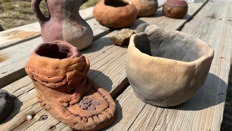 A clay shaped like a traditional moose hide moccasin among mugs and vases. 