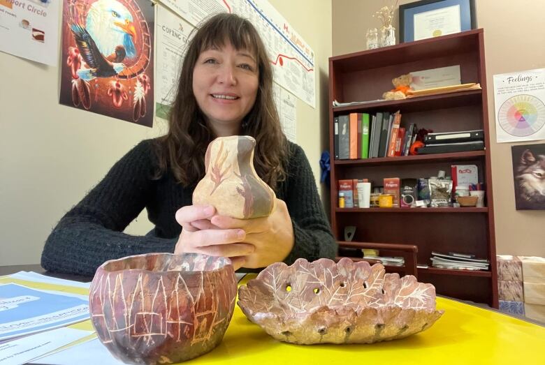 A woman shows a collection of decorative clay creations.