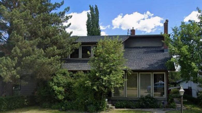 a home with a large roof and two large trees in front of it