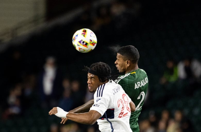 Two men collide under a soccer ball