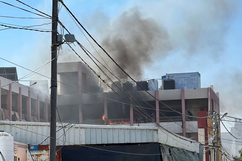 Grey smoke billows from a school sheltering displaced people.