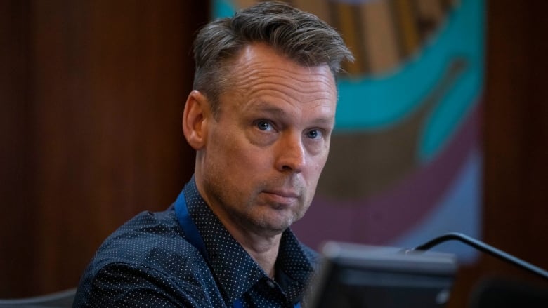 A man in a blue shirt behind a screen