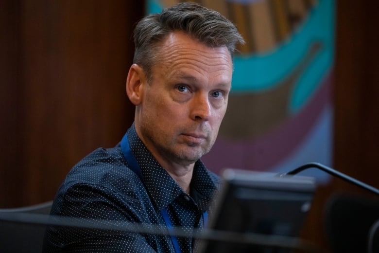 A man in a blue shirt looks up from a computer screen