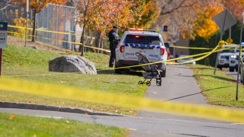 A green space taped off with police tape. A single child's stroller stands alone.