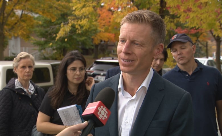 Man with red hair, wearing a suit talks into a microphone