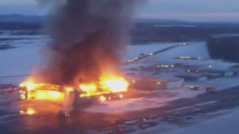 A hangar is completely aflame on a snowy night