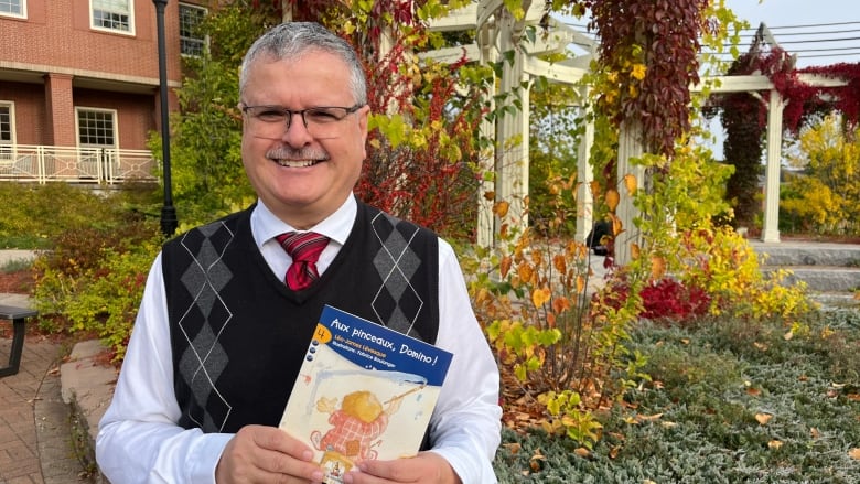 A smiling man holding a book