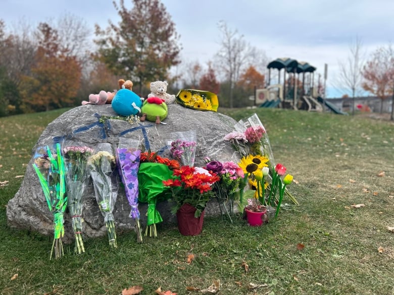 Flowers rest against a rock. A children's play structure can be seen in the background. 