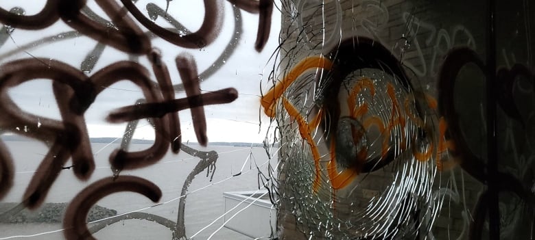 A smashed window with graffiti.