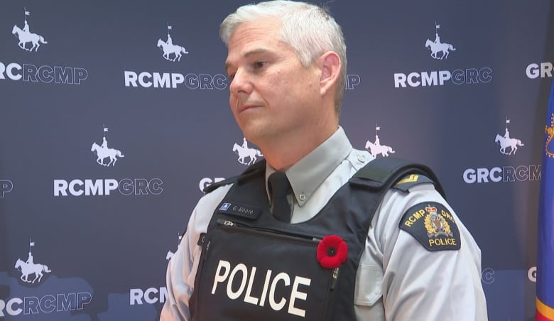 White-haired man in Mountie uniform stands in front of an RCMP backdrop.