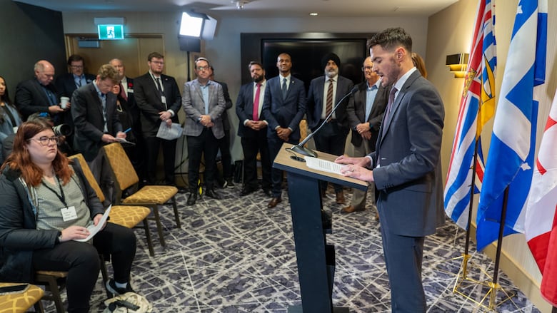 A man stands at a podium while several people watch