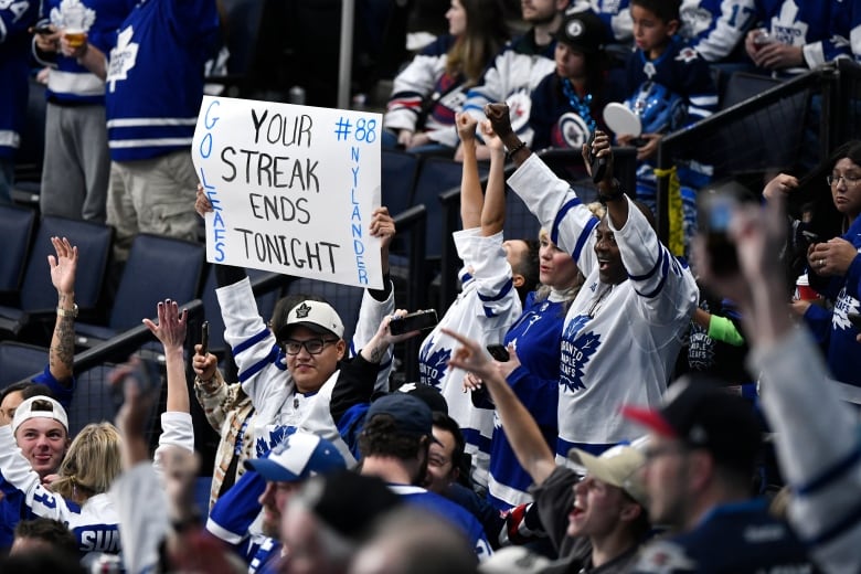 A group of people in white hockey jerseys holding signs.