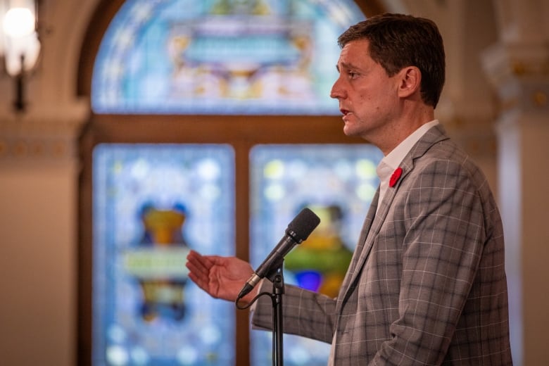 A man wearing a plaid suit speaks into a microphone.