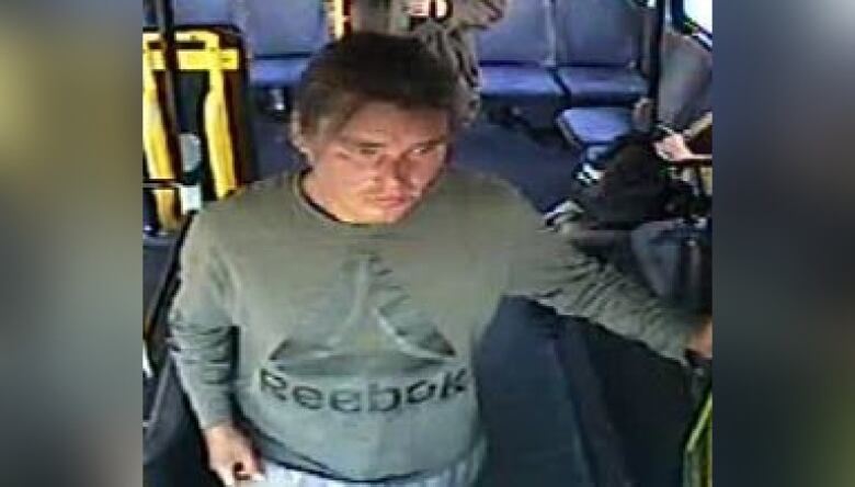 Surveillance of a man wearing a green long sleeved shirt riding a bus. 