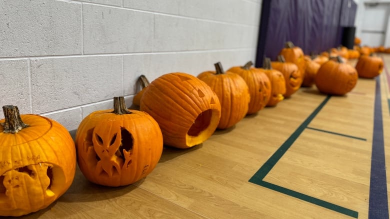 Multiple pumpkins lined against the wall