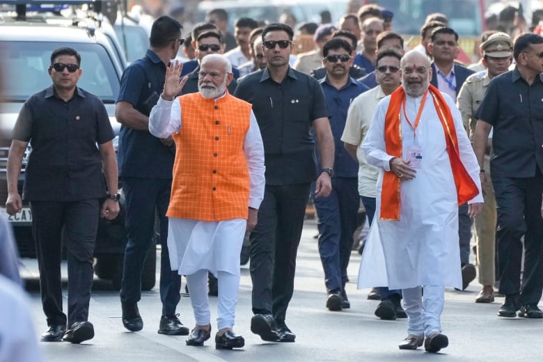 Indian Prime Minister Narendra Modi, wearing saffron jacket along with Home Minister Amit Shah, wearing saffron shawl, arrives to cast his vote during the third phase of general elections, in Ahmedabad, India, Tuesday, May 7, 2024.