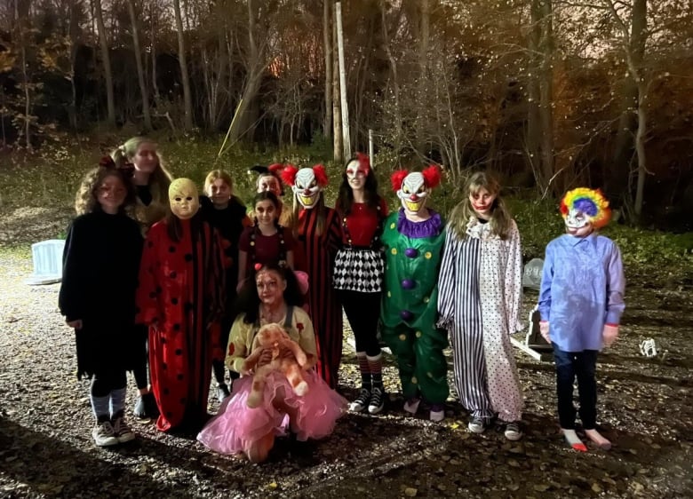 A group of volunteers wearing halloween costumes stand in a dark forest.