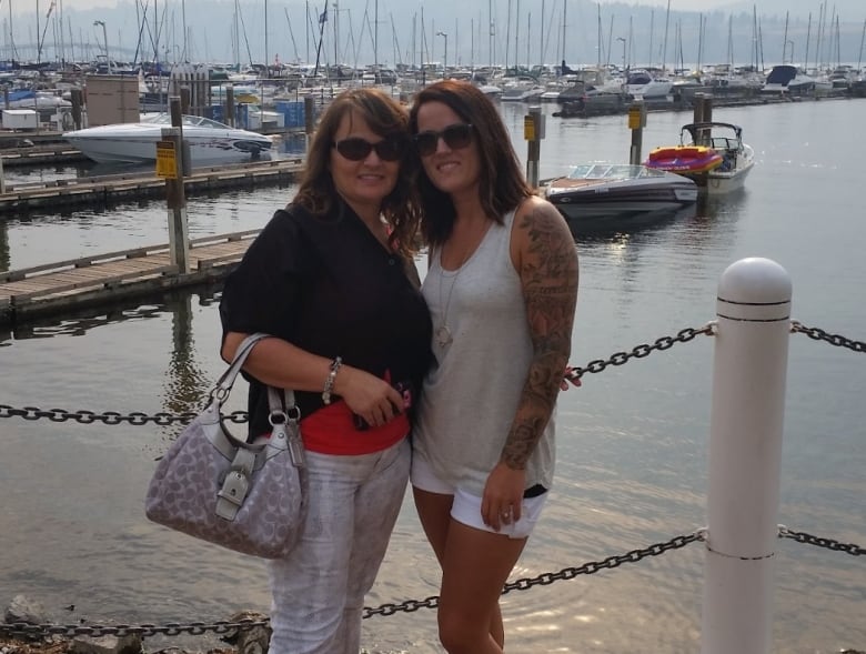 Two women pose for the camera on a waterfront