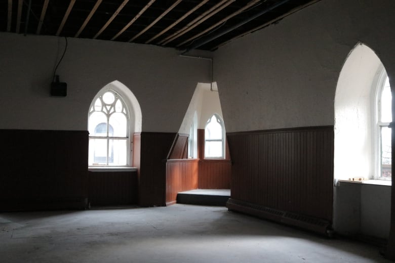 An empty room with three windows has visible signs of renovation efforts.