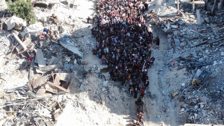 A group of people stand near rubble