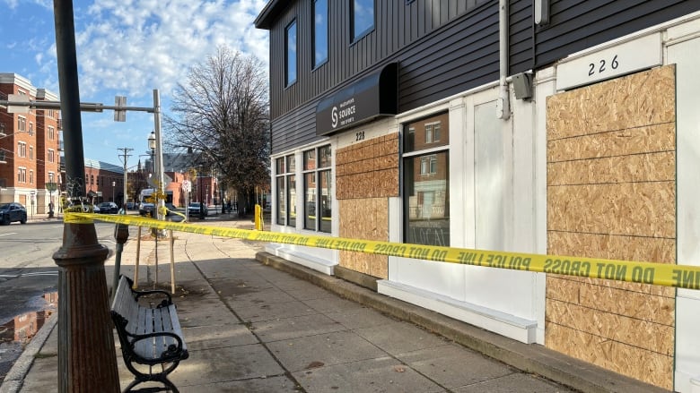 A building with boards on the front and caution tape around it.