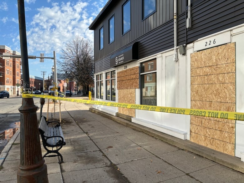 A building with boards on the front and caution tape around it.