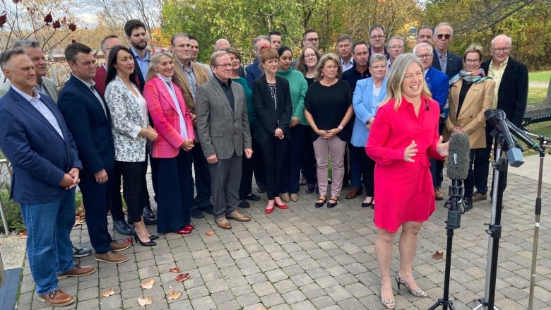 A woman standing at a microphone with a group of people standing behind her.