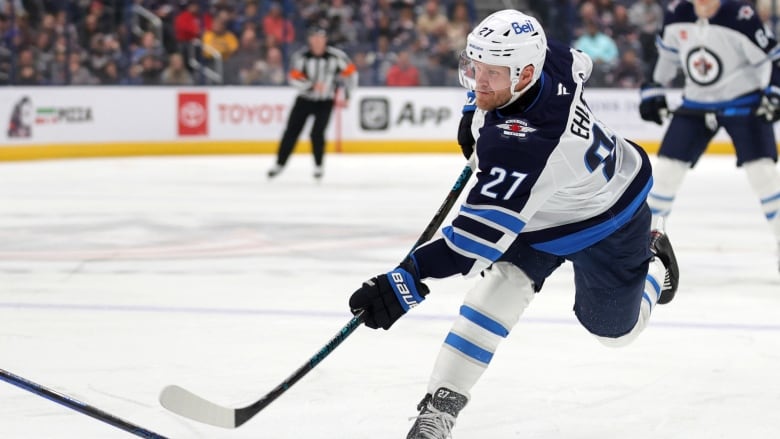 A hockey player is pictured shooting a puck.