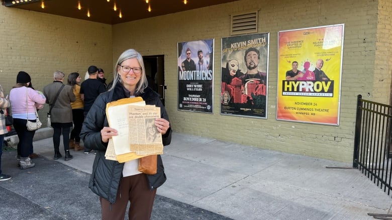 A woman holding a folder as well as a newspaper clip