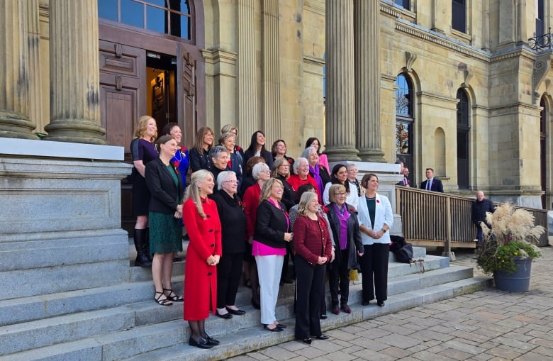 A group of women stand on the legislature steps.