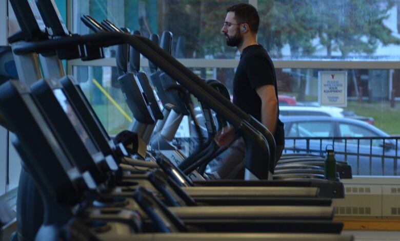 A man walks on a treadmill in a row of empty treadmills 