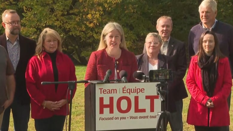 Woman standing at podium with row of people behind her. 