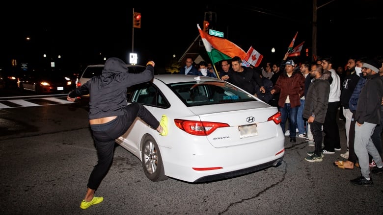 A young person taking part in a march kicks a car after it honked at members of Bramptons Hindu community, who were blocking traffic, near the Hindu Sabha temple on Nov. 4, 2024.