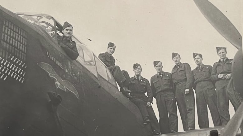 Black and white image of military men on the wing of a large airplane