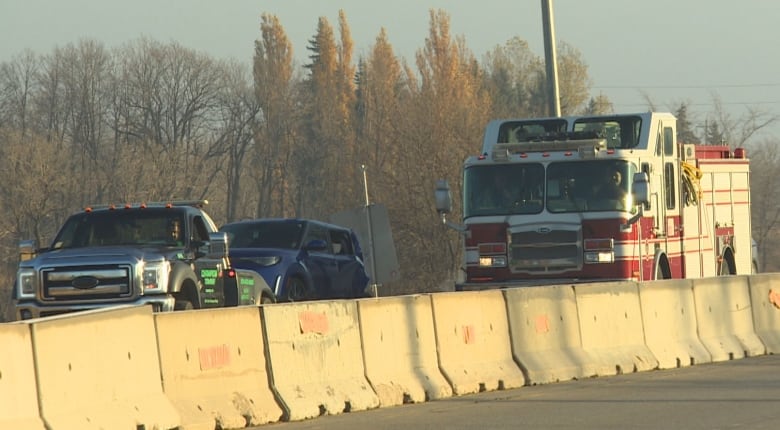 A tow truck removes a car involved in a crash while a fire truck is parked behind.