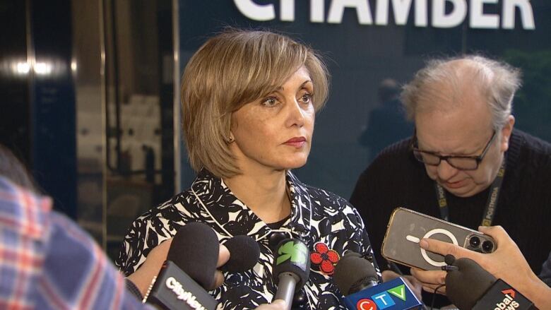 A woman stands in front of a number of reporters.