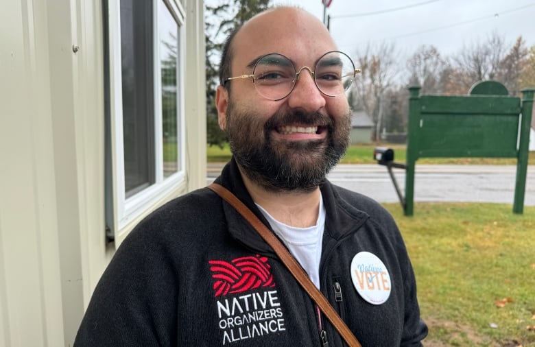 A man with a beard and glasses smiles for the camera 