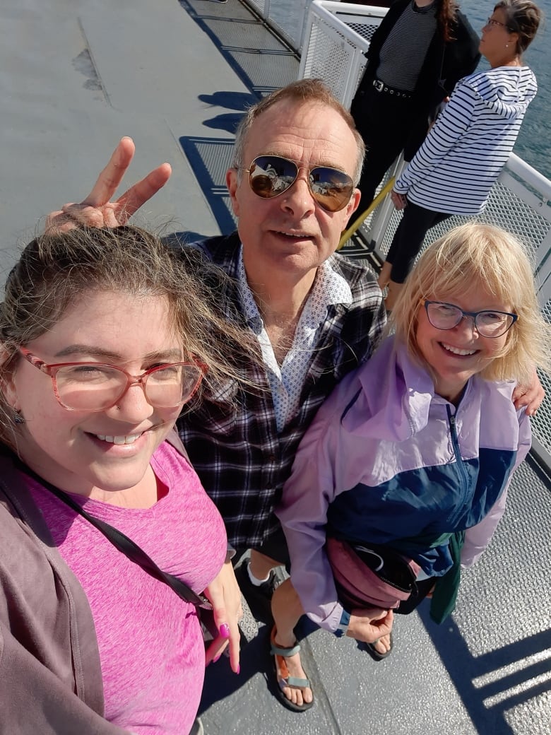 A selfie of two women and a man on a ferry, all of whom are smiling.