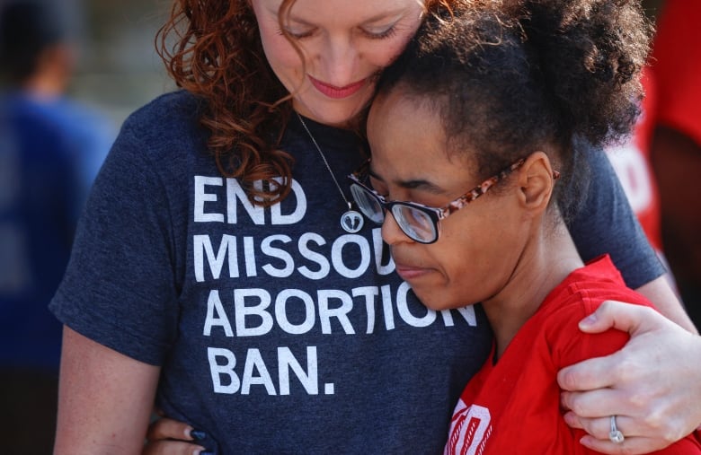 Two women hug.