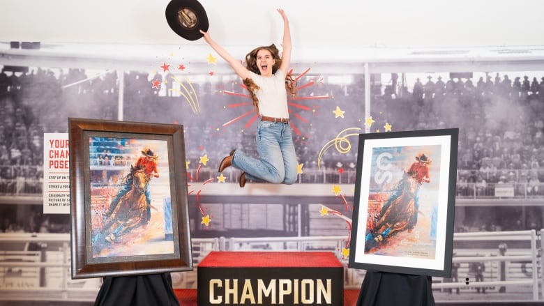 A young woman wearing jeans and holding a cowboy hat jumps in the air. Two copies of her prize-winning painting are on either side of her. 