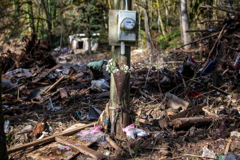 A small bouquet of flowers lies on a post, surrounded by wreckage and debris.