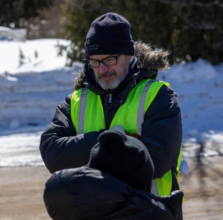 A man in a highlighter yellow vest and a beanie.