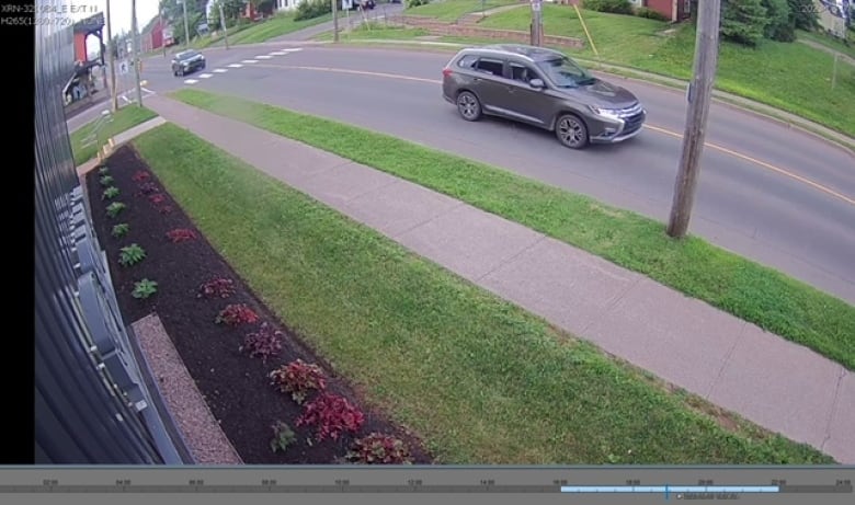 A grey SUV shown in a still photo from surveillance footage on a city street.