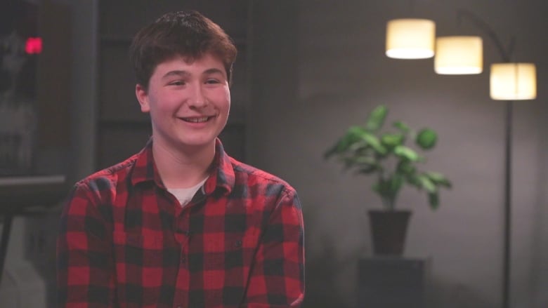 A smiling boy wearing a red, plaid shirt