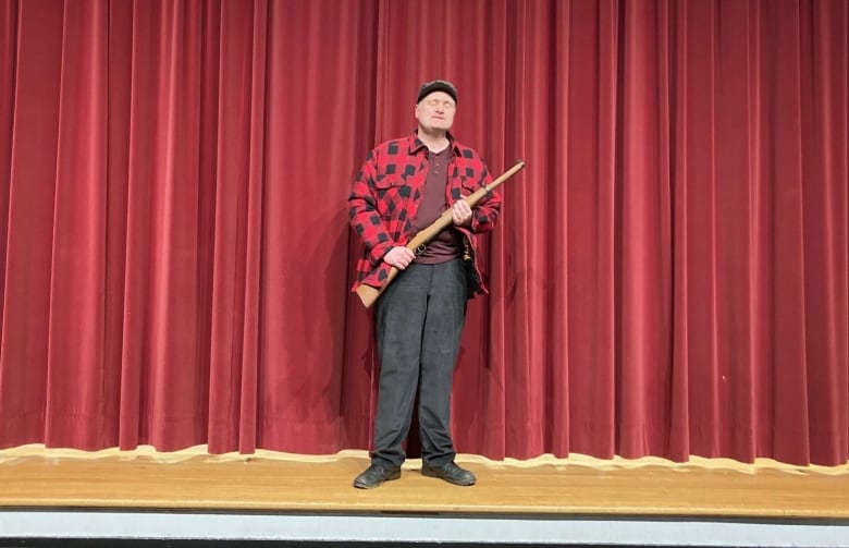 A man standing on a stage with a fake gun in his arms