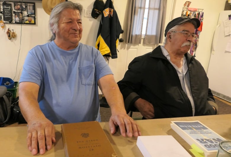 Bros sitting at table w WWII 42nd Division Handbook.