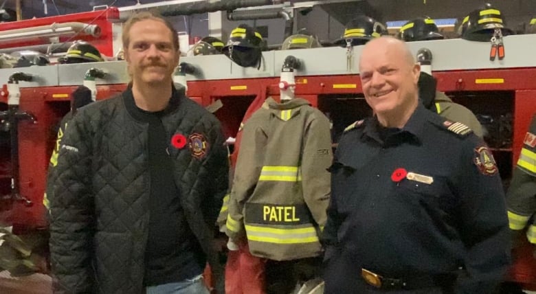 two men standing infront of fire fighting gear