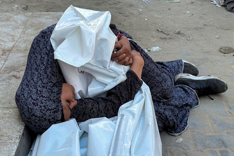 A relative embraces the body of a Palestinian killed in Israeli fire, amid the ongoing Israel-Hamas conflict, at Kamal Adwan hospital in Jabalia, in the northern Gaza Strip October 21, 2024. 