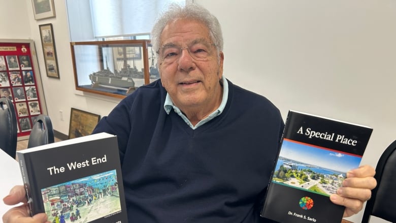 An older man holding two books.