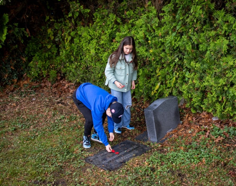 Two children lay poppies on a gravestone.